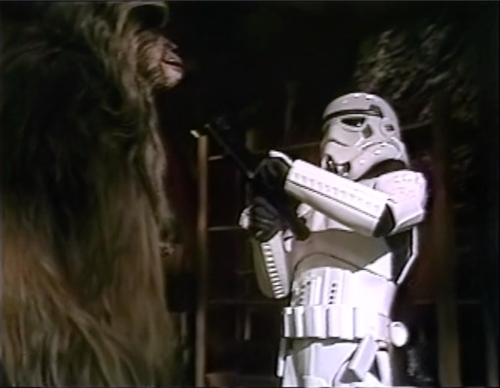 A stormtrooper points a blaster at Malla the Wookiee. Star Wars Holiday Special