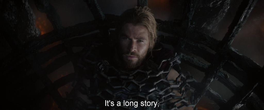 Thor, wrapped in chains in a cage, looks directly into the camera. 